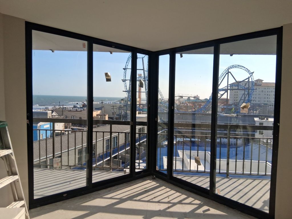 Corner black aluminum sliding glass door system inside Ocean Colony with panoramic boardwalk and ocean view