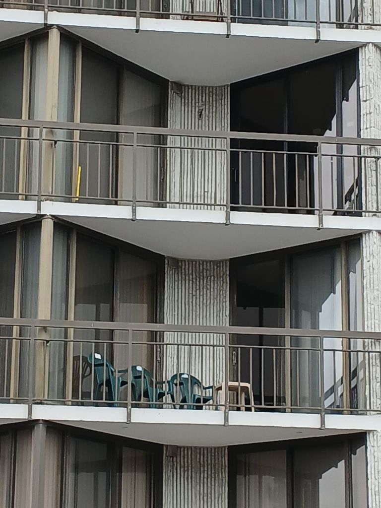 Ocean Colony balcony close-up showing bronze anodized sliding glass door replacements across multiple floors