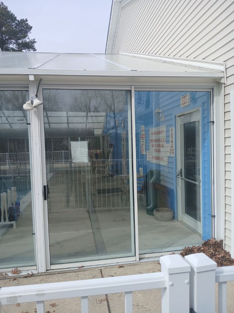 Pool enclosure exterior white aluminum framed glass panels with safety signs