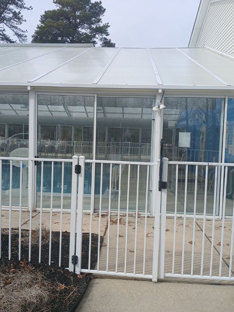 Pool enclosure exterior with white aluminum framed glass sliding doors and safety fence