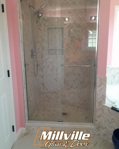 Residential custom shower glass door with herringbone tile